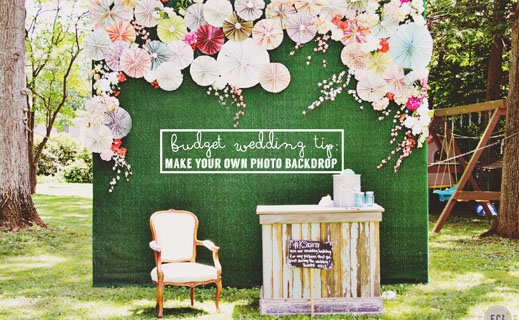 Outdoor photo booth setup with a decorative backdrop and a vintage chair and table